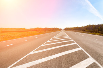 The picturesque landscape and the Sunrise over the road. Asphalt road with marking. With the blur...