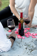 Wine bottle with wine glasses with rose petals with people