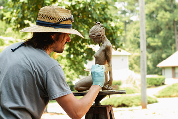 artist applying patina to sculpture