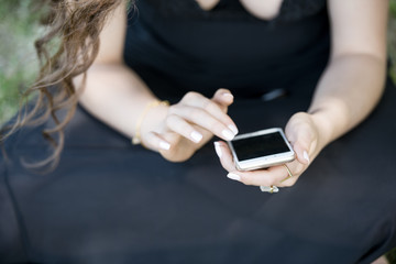 Woman sitting on the ground holding a smartphone typing a message