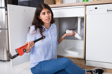 Woman Holding Sink Pipe And Monkey Wrench