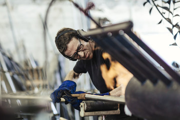 Man placing steel poles in forge