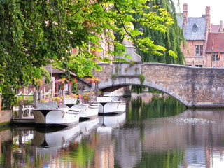 Fototapeta na wymiar Three Boats Await Passengers in Canal in Bruges, Belgium
