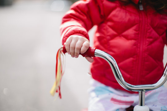 Cute toddler holding on to the handlebar of a tricycle