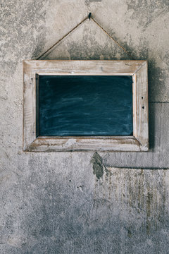 Blackboard Hanging on an Old, Rustic Concrete Wall