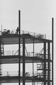 Construction worker leaning against a pillar on top of a tower