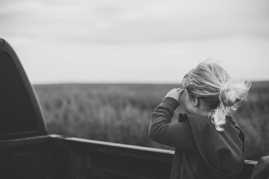 Little girl rides in back of truck.