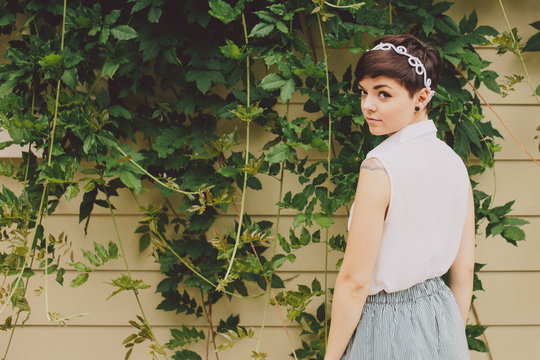 Girl with short hair in front of vines