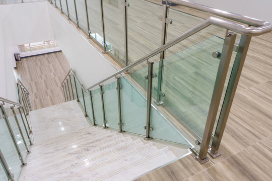 Modern white marble stairs with steel and glass railing in a new modern building.