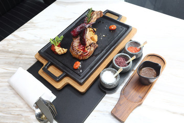 Pork Chop with three kind of salt and sauce, on heat plate wooden under, American Style Luxury Restuarant