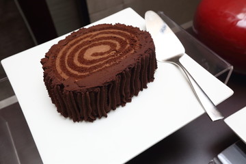 Mulberry Chocolate Cake Big Roll Cream in Catering White Dish with silver cake spatula, Grand Dessert Buffet in Luxury Restaurant Hotel
