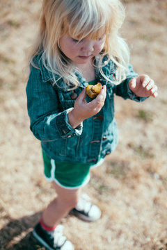 A little girl stands and eats a fresh plum.