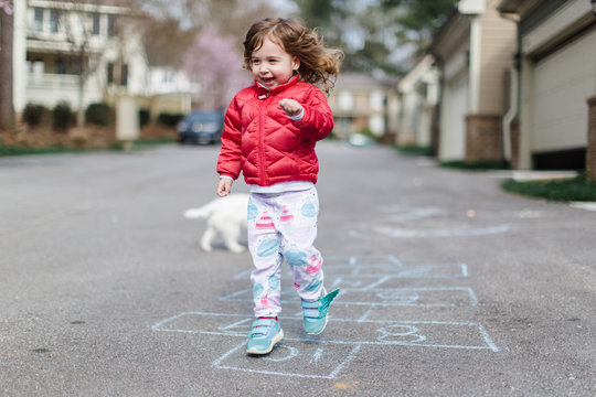 Cute toddler doing hopscotch outside