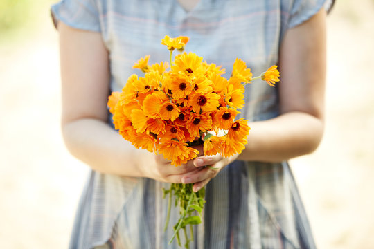 Woman holding calendula flowers for aromatherapy