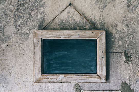 Blackboard Hanging on an Old, Rustic Concrete Wall