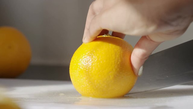 Female hands slicing oranges, in slow motion