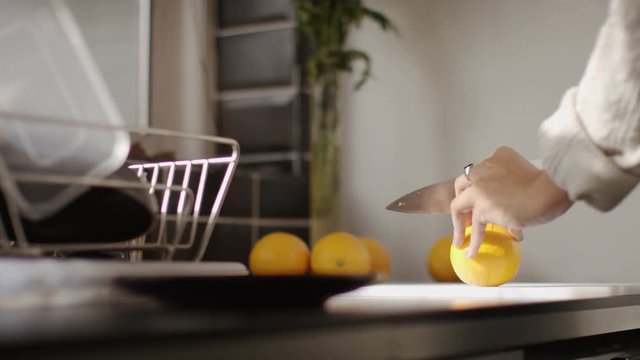 Young woman in a kitchen slicing up oranges