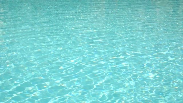 Shiny bright blue water in the swimming pool. Surface of water in the pool. Slow motion.