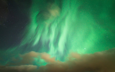 Fototapeta na wymiar The strong bright Aurora borealis (Northern lights) over the sky in Iceland.