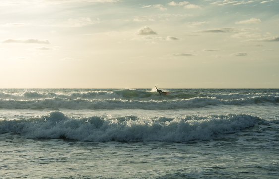 Surfer cutting back on a wave with sun behind him