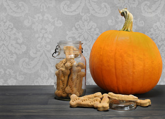 Homemade pumpkin dog cookie bones in a canning jar next to a pumpkin.