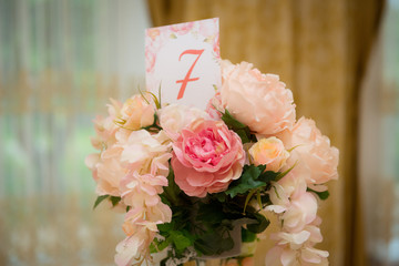 Number seven on the card in the bouquet of flowers on the table