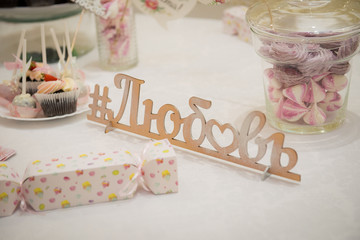 The word Love in Russian is carved out of wood on the table among the sweets