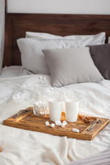Two mugs on a tray white bed with a cinnamon stick, breakfast concept