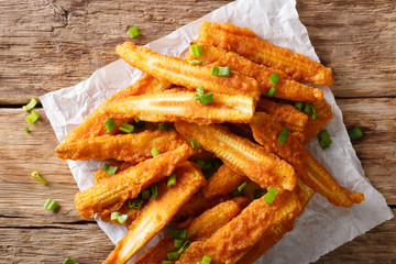 Fast food: fried baby corn with green onions close-up on the table. Horizontal top view