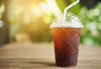 Cold iced black coffee on wooden table in the garden background.