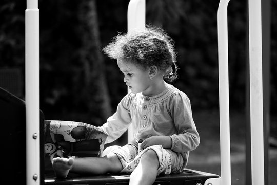 Portrait of young child coloring intently at a park