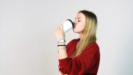 Young beautiful woman drinks from white cup of coffee on white background. Beautiful woman drinks from a coffee cup