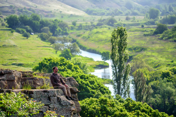 Fototapeta na wymiar Traveler sitting on edge of rock