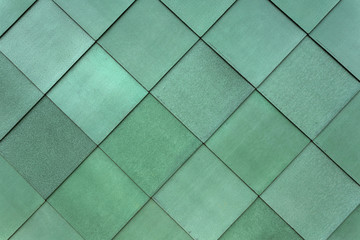 Square green cladding fastened to the exterior of a building to form a pattern