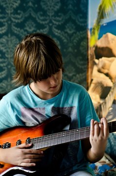 Boy is playing electric guitar in retro room of his parents