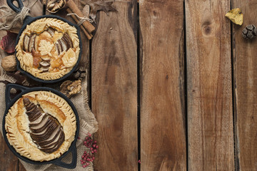 pie with a pear in a frying pan on a brown wooden background