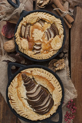 pie with a pear in a frying pan on a brown wooden background