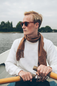 Elegant young man rowing in a lake