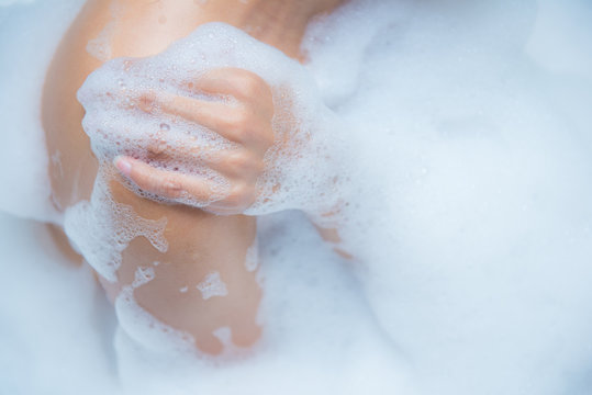 Young woman taking a relaxing bath with foam