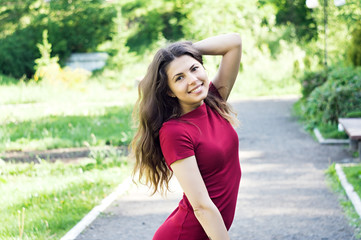 Beautiful girl model in a park on the road posing for photo camera in red board