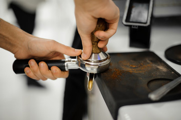 Professional proper tempering, pressing of ground coffee in the holding