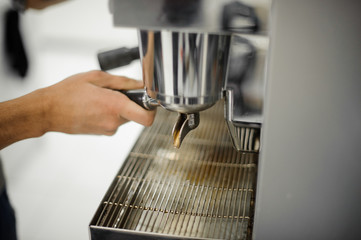 Male barista making coffee with help of coffee machine