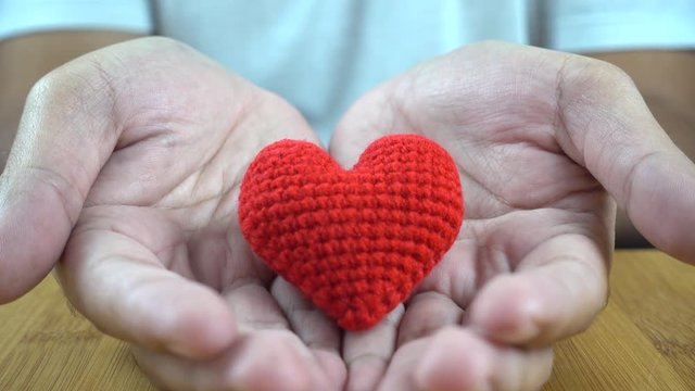 close up of man cupped hands showing one red heart