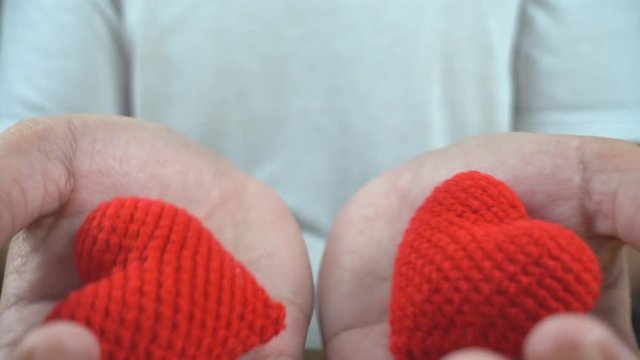 close up of man cupped hands showing two red heart