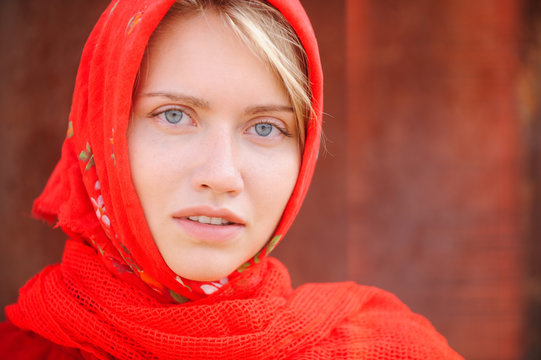 A russian blonde with blue eyes in a red kerchief is working on the farm. The concept of female beauty and perfection, russian beauty.