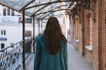 Portrait of a beautiful brunette girl in coat. View from back.