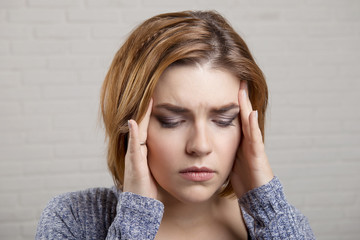 Girl holds hands at the temples with the emotion of pain in the head Close-up Studio portrait