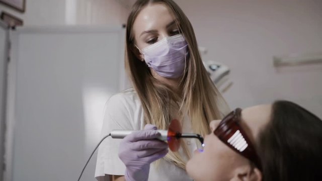Dentist makes a procedure with a dental polymerization lamp to a patient