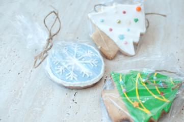 Three Christmas gingerbread cookies in the different shapes in a cellophane packing on the background of a wooden table. Close-up, selective focus, bokeh, copy space. Christmas gift concept.