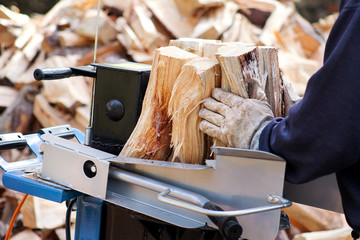 Saw cutting wood for winter. A man cutting firewood for the winter using a modern machine lumber saw. Wood industry. Heating season, winter season. Renewable resource of energy. Environmental concept.